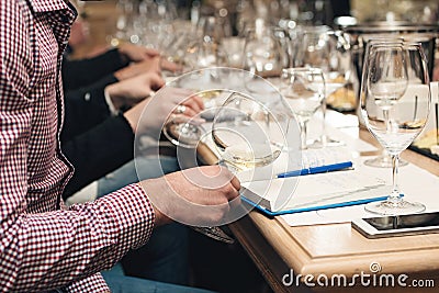 People consider the color of the wine and try how it smells in different glasses. Man making notes. Stock Photo