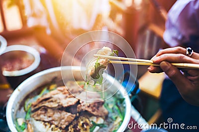 People cooking meat and grill. Food are vegeteble. People use chopsticks. Stock Photo