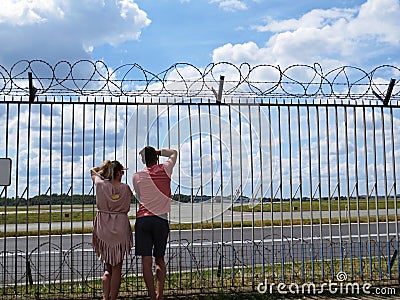 People Couple Guy and Girl in Love Together Looking Watching Planes at Airport through Fence with Barbed Wire Editorial Stock Photo