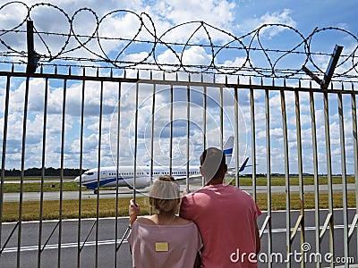 People Couple Guy and Girl in Love Together Looking Watching Planes at Airport through Fence with Barbed Wire Editorial Stock Photo