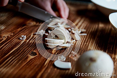 People cut mushrooms with a knife.The slices are adjacent. Wooden surface Stock Photo