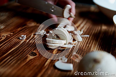 People cut mushrooms with a knife.The slices are adjacent. Wooden surface Stock Photo