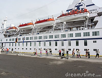 People dancing beside their cruise ship in the harbour Editorial Stock Photo