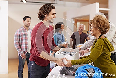 People Donating Food To Charity Food Bank Collection In Community Center Stock Photo