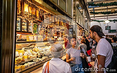 People drinking coffee in front of a cheese shop inside Queen Victoria Market aisle in Melbourne Australia Editorial Stock Photo