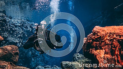 People snorkeling and diving in Blue crystal clear glacial water in Silfra Thingvellir national park Iceland Stock Photo