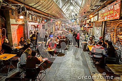 People eat and drink on a food court in the evening at the Machane Yehuda Market in Jerusalem, Israel Editorial Stock Photo