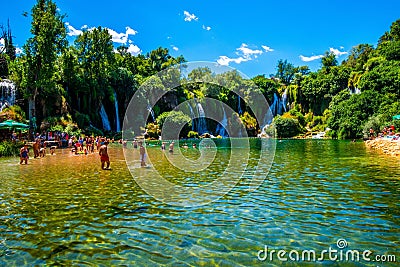 people at the edge of a river and waterfall in the distance Editorial Stock Photo