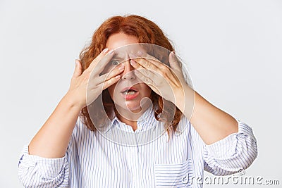 People, emotions and lifestyle concept. Close-up of shocked and alarmed redhead middle-aged woman cover eyes as being Stock Photo