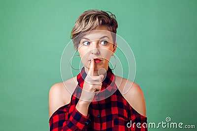 People and emotions - a portrait of woman with short dark hair with finger near lips showing hush silence sign Stock Photo