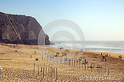 People enjoy a relaxing afternoon at the golden Praia das Macas on the Atlantic Ocean Editorial Stock Photo