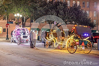 people enjoy to have a ride by night in the horse drawn carriage with colorful neon light in San Antonio at the river walk area Editorial Stock Photo