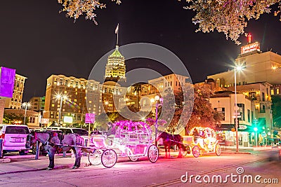 people enjoy to have a ride by night in the horse drawn carriage with colorful neon light in San Antonio at the river walk area Editorial Stock Photo