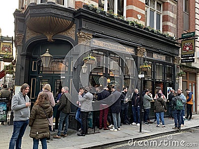 Typical pub with clients seated and standing outside in the city of London , England Editorial Stock Photo