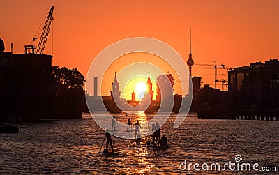 People enjoying summer in Berlin on river with sunset sky, Oberbaum Bridge, Tv Tower Stock Photo