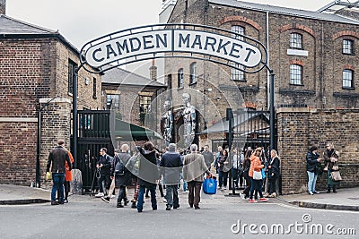 People entering Camden Market, London, UK, through the gates, under a name sign Editorial Stock Photo