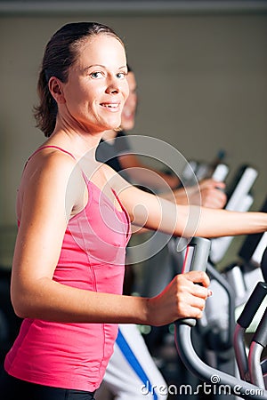 People exercising on elliptical trainer in gym Stock Photo