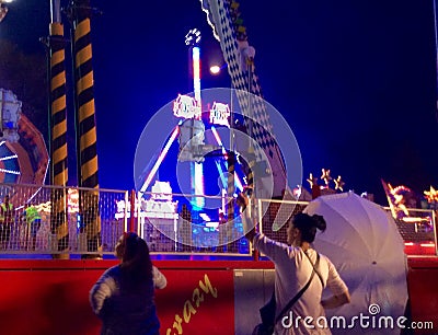 People at a fair watching others on a fun ride, waving Editorial Stock Photo