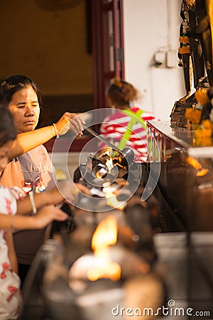 People fill oil on lantern in Wat Rakhang Khositaram Editorial Stock Photo