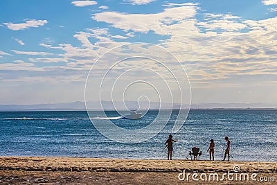 People fishing silhouetted against the water of the bay as a motorboat speeds by with opposite shore barely visible on horizon Editorial Stock Photo