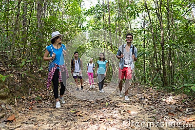 People Group With Backpacks Trekking On Forest Path, Young Men And Woman On Hike Stock Photo