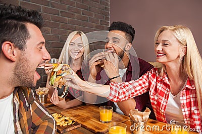 People Group Eating Fast Food Burgers Sitting At Wooden Table In Cafe Stock Photo