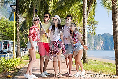 People Group Take Selfie With Action Camera On Stick While Walking In Palm Tree Park On Beach, Happy Smiling Mix Race Stock Photo