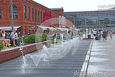 People have a rest near city fountains. Jets of water at fountains in summer day Editorial Stock Photo