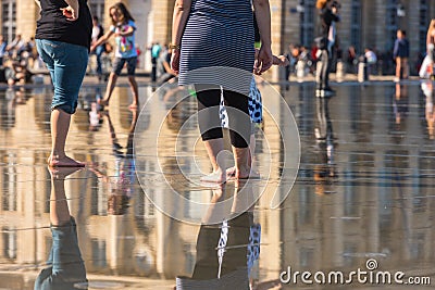 People having fun in a mirror fountain in Bordeaux, France Stock Photo