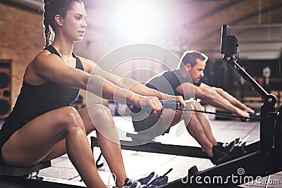 People having hard workout on rowing machines Stock Photo