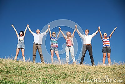 People on hill raise hands together Stock Photo