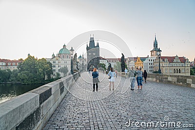 People and historic statues at sunrise of famous Charles Bridge against backdrop of city architecture Editorial Stock Photo