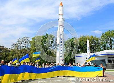 People hold large flags of Ukraine against rockets in city Dnipro - space center of Ukraine. Patriotic people with Ukrainian flags Editorial Stock Photo