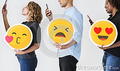 People holding emoticons and mobile devices Stock Photo