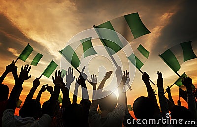 People Holding Flag of Nigeria in Back Lit Stock Photo