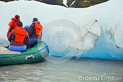 PEOPLE ON INFLATABLE RAFT INSPECTING A GLACIER ICE FLOE Editorial Stock Photo