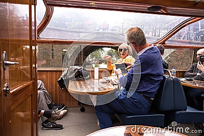 People on interior seating inside a glass roofed sightseeing canal cruise trip boat for tourists Editorial Stock Photo