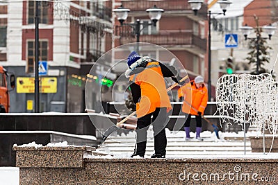 People-janitors in orange jackets cleaned the city from snow with shovels. Winter city after a snowfall Editorial Stock Photo