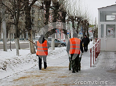 People janitors workers sprinkle slippery streets in the city with sand in winter against ice Editorial Stock Photo