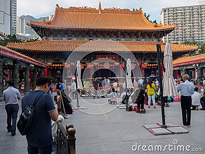 People are kneeling and praying in front of the Wong Tai Sin temple in Hong Kong Editorial Stock Photo