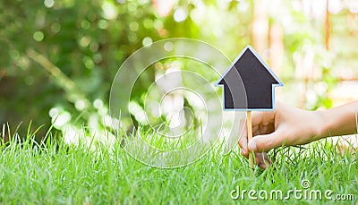 People are lacing House symbol with location pin and green grass in real estate sale or property investment concept, planning Stock Photo