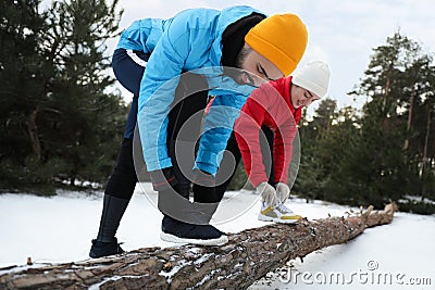 People lacing sneakers on log in winter forest. Outdoors sports exercises Stock Photo