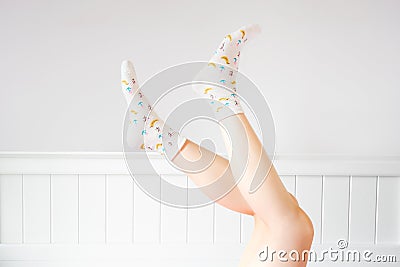 People Legs Up on White Bedroom Studio. Closeup of the Bare Leg of a Beautiful Young Woman Wearing Bright Cute Pastel Stock Photo