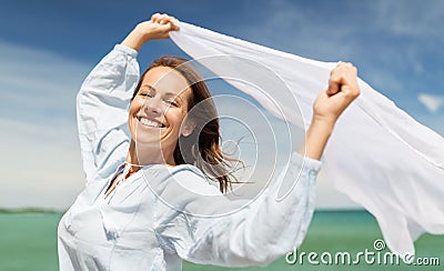 Happy woman with shawl waving in wind on beach Stock Photo