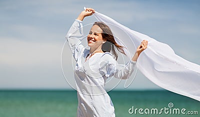 Happy woman with shawl waving in wind on beach Stock Photo