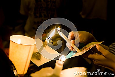 People lighting candle vigil in darkness seeking hope, worship, Stock Photo