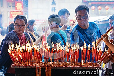 People lighting candles in Wat Mangkorn Kammalawas Leng Nuei Yee , Bangkok, Thiland Editorial Stock Photo