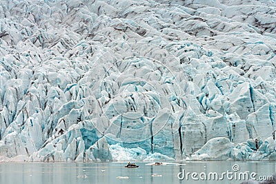 People in little inflatable rubber boat close to Vatnajokull glacier in Fjallsarlon glacier lagoon in Iceland. Stock Photo