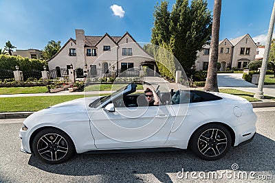 People luxury lifestyle concept. Young adult man driving convertible car in luxury houses neighborhood Stock Photo