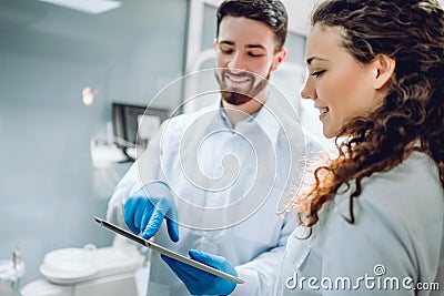 People, medicine, stomatology and health care concept - happy male dentist showing tablet pc computer to woman patient at dental Stock Photo